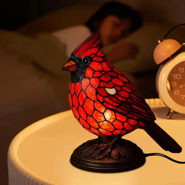 A decorative resin bird table lamp shaped like a red and black bird sitting on a wooden base.