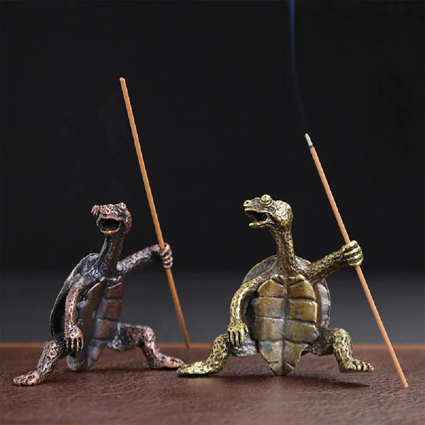 A small metal turtle figurine is shown with smoke rising from it, set against a dark background.