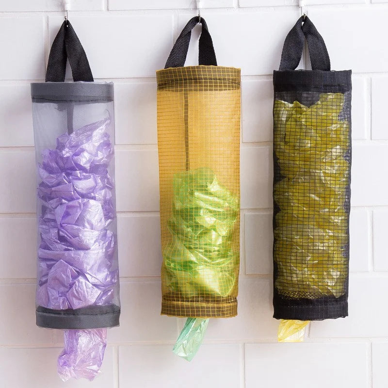 Trois distributeurs de sacs d'épicerie muraux remplis de sacs en plastique violet, vert et jaune.