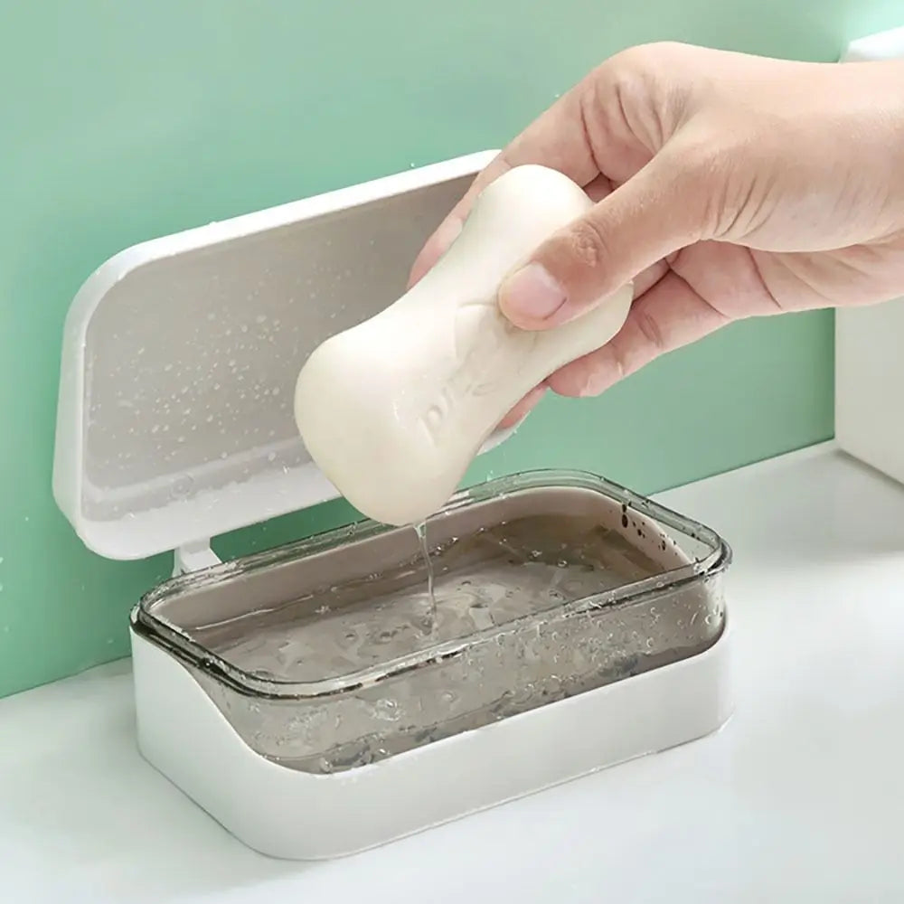 A hand is pouring soap from a white dispenser into a transparent drainage soap dish.