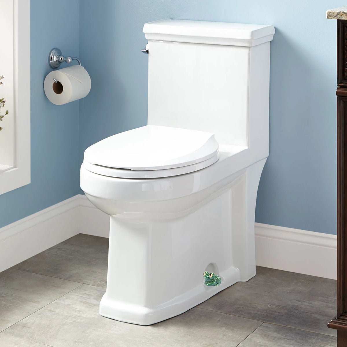 A white ceramic toilet with decorative bolt covers is shown against a light blue wall.