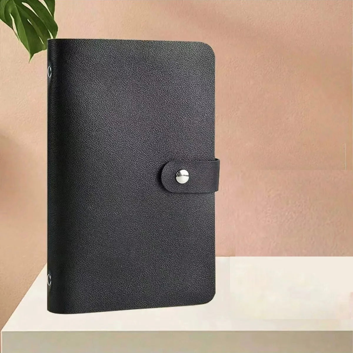 A black cash organizer ledger with envelope sleeves resting on a white surface.