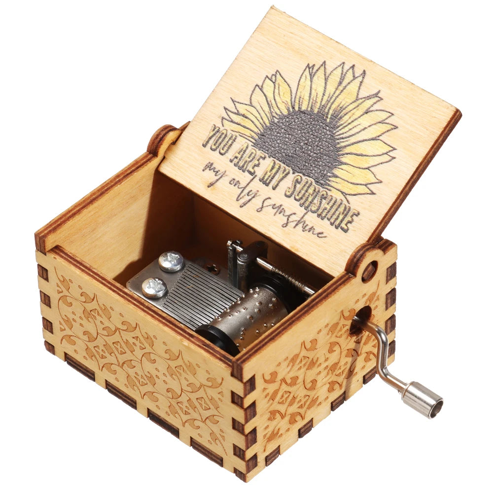 A vintage engraved wooden music box with a lid featuring a sunflower design and a small metal mechanism.