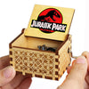 An antique wooden hand crank music box with a lid featuring the Jurassic Park logo.