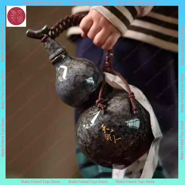 A hand holds a dark ceramic gourd cup set with a dragon design against a blurred background.