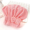 A pink microfiber hair drying cap and towel is displayed in a wire basket.