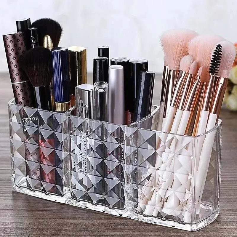 Clear acrylic makeup brush holder with three compartments filled with various makeup brushes
