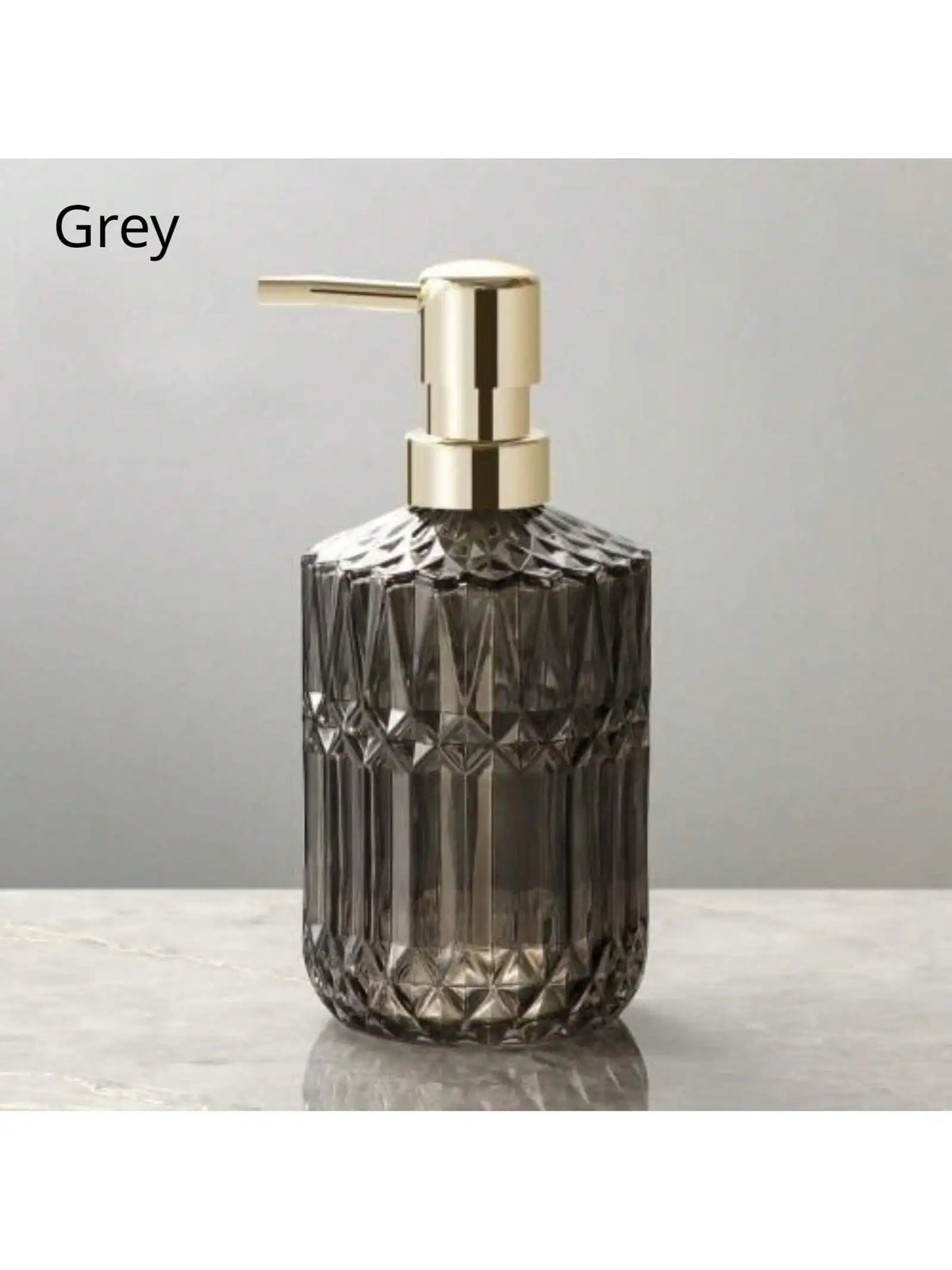 Glas-Seifenspenderflasche mit goldfarbener Pumpverschluss vor grauem Hintergrund