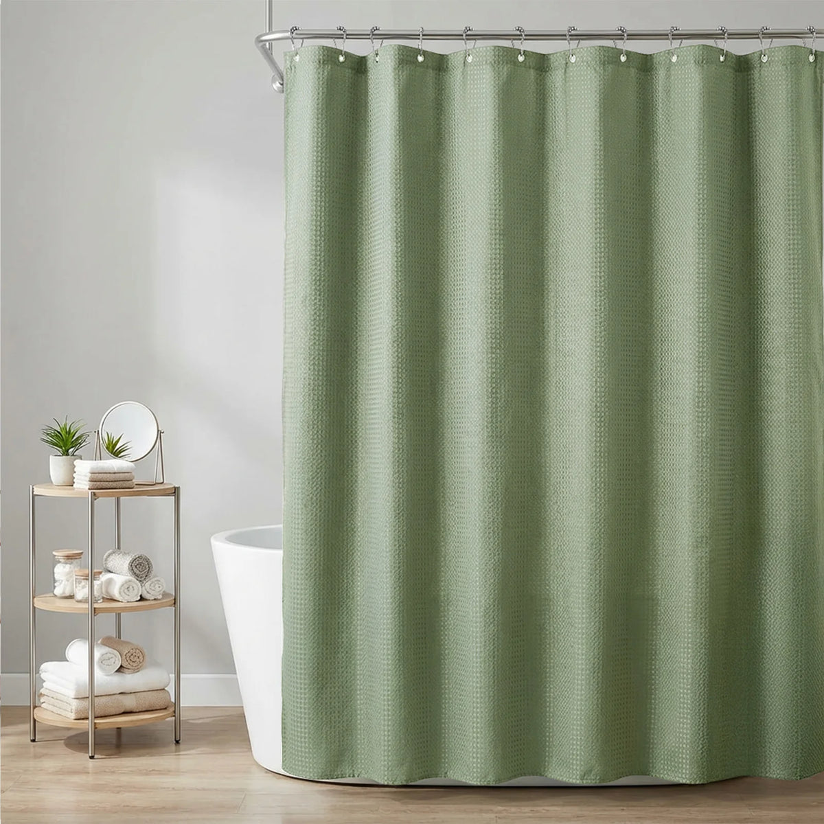 A light sage green waffle weave shower curtain hanging on a metal rod in a bathroom setting.