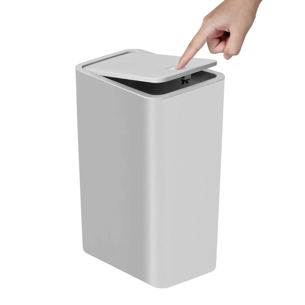 A hand is pressing the lid of a small, rectangular trash can with a press-fit mechanism.