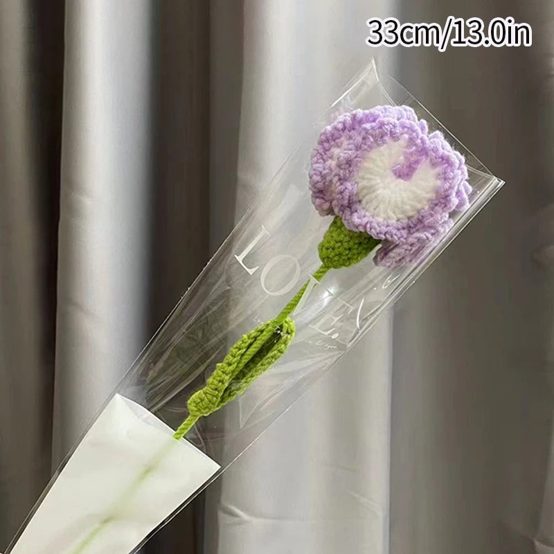 Bouquet de cœurs de carnais faits main avec des pétales violets et une tige verte, emballé dans du plastique transparent.