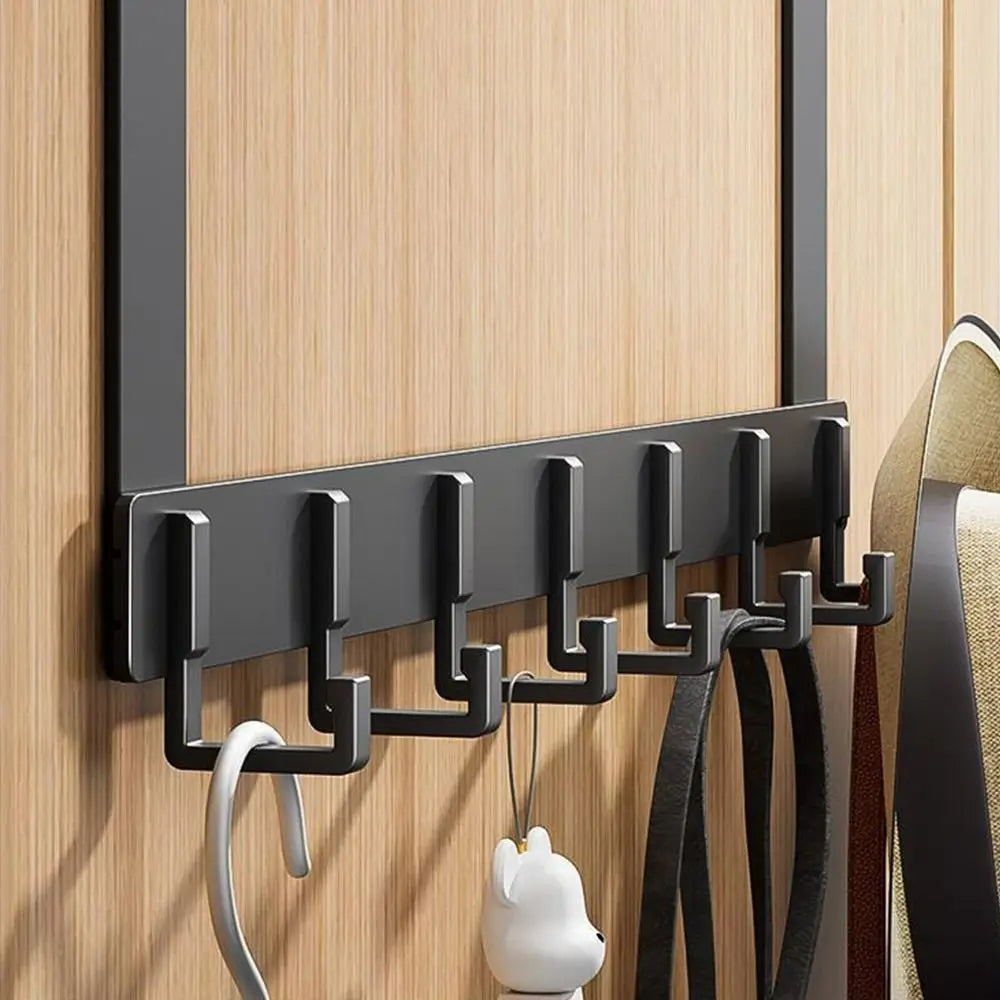 A black heavy-duty adhesive door hook rack mounted on a wooden surface, holding several black straps and a white pet collar.