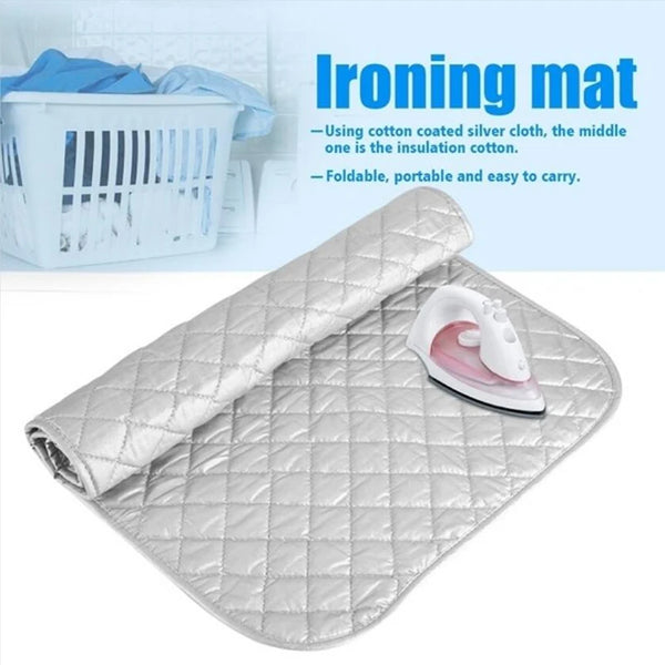 A silver quilted ironing mat with a rolled cloth and a steam iron placed on it.