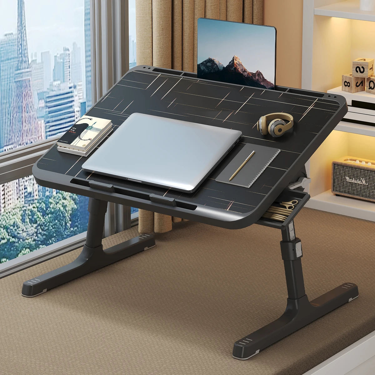 Una bandeja y reposapiés de madera ajustable para portátil con una laptop y auriculares plateados sobre un escritorio.