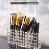 Clear acrylic makeup brush holder with three compartments displaying various makeup brushes.