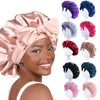 A woman models a silky satin sleep bonnet with various colored bows and styles for curly hair.