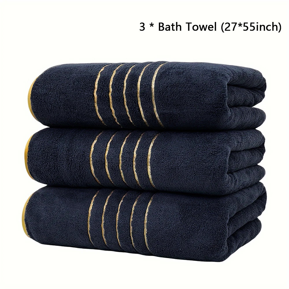 Three dark blue bath towels with gold stripes stacked neatly.