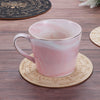 Pinke Keramiktasse mit weißem Marmorglas auf einem Holzpendelbrett mit Monaten.