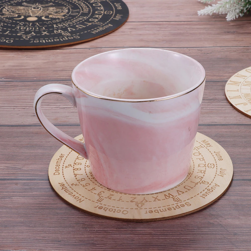 Pinke Keramiktasse mit weißem Marmorglas auf einem Holzpendelbrett mit Monaten.