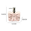 A pink ceramic pump dispenser bottle with a bowknot design and silver pump top.