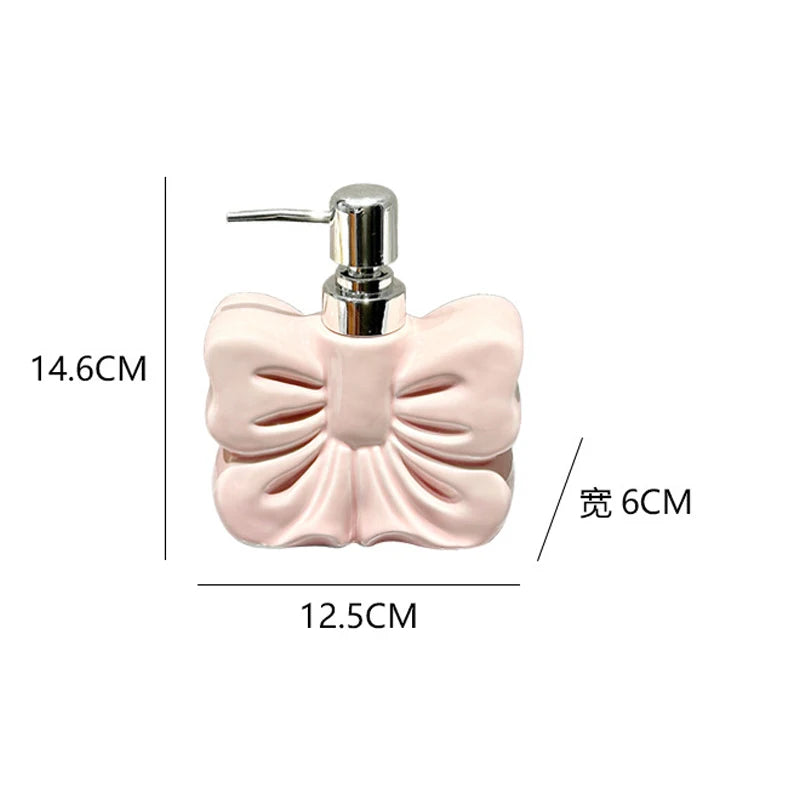 A pink ceramic pump dispenser bottle with a bowknot design and silver pump top.