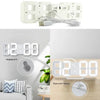 A white digital alarm clock with a removable bracket and hanging hole is shown on a wooden surface.