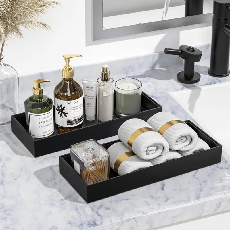 A set of black silicone trays organizing soap and bathroom products on a marble countertop.