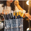 Clear acrylic makeup brush holder with three compartments filled with various makeup brushes