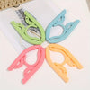 A set of five portable foldable clothes hangers in shades of light green, blue, and orange arranged on a white surface.