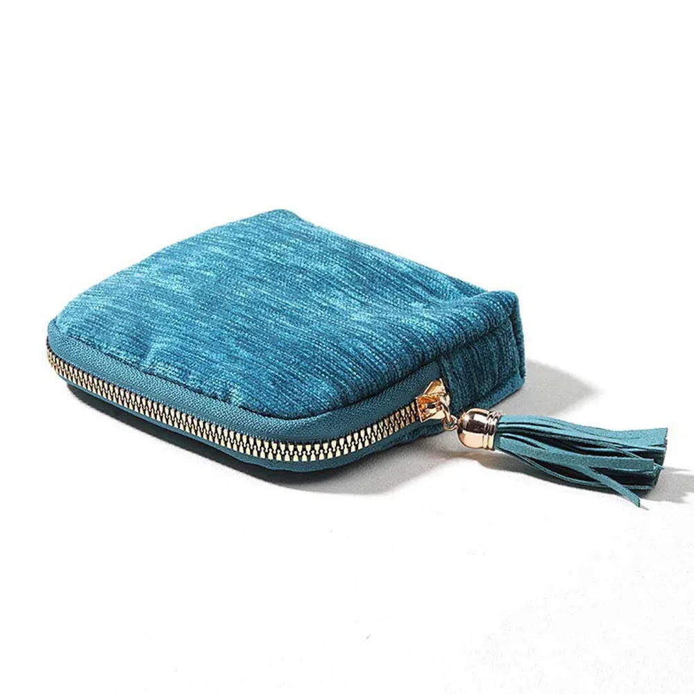 A teal velvet jewelry storage bag with a gold-toned zipper and tassel detail.