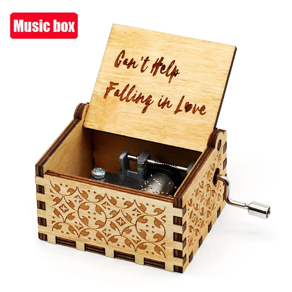 An antique wooden music box with a lid engraved 'Can't Help Falling in Love' and a visible hand crank mechanism.