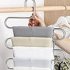 A multi-layer stainless steel clothes rack holding various folded white and beige fabric items.