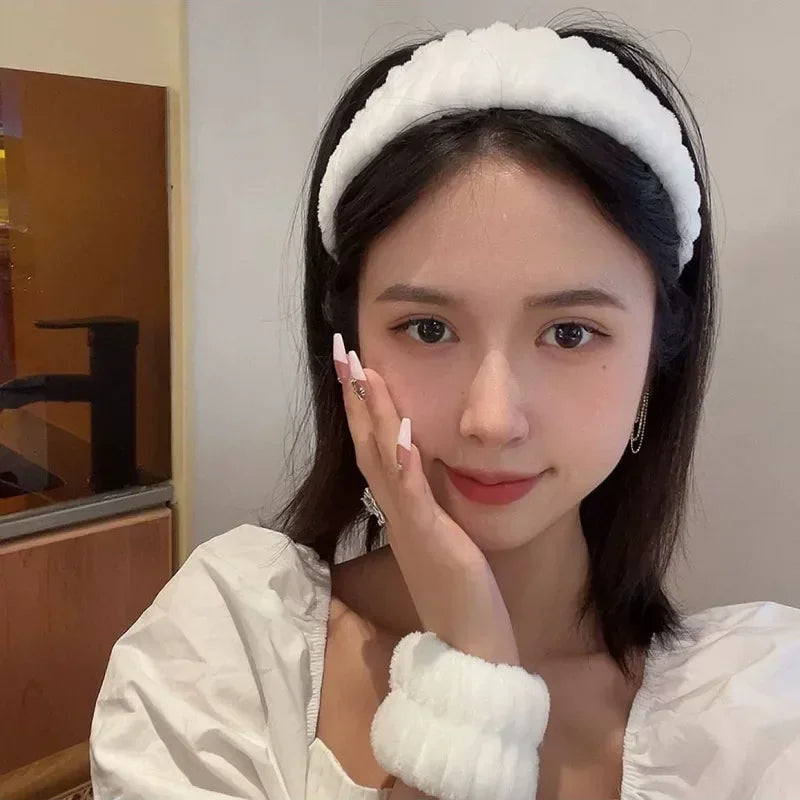 A young woman wearing a white microfiber wrist sweatband set for face washing and skincare.