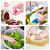 Hands wearing pink nitrile cleaning gloves prepare food ingredients like pomegranate seeds and fresh vegetables.
