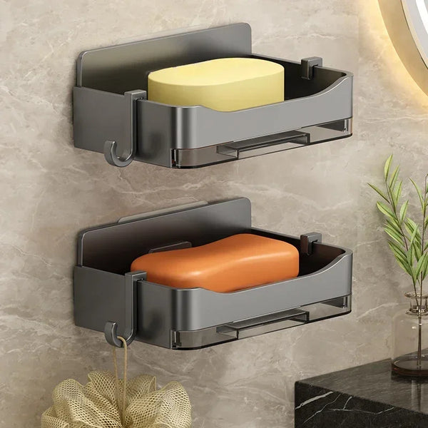 A wall mounted bathroom soap holder with a rectangular ceramic soap in an open metal tray.