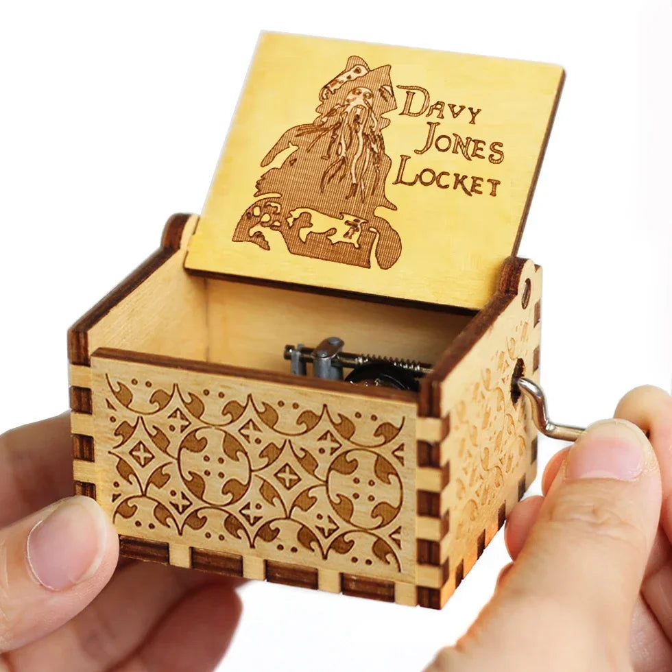 An antique wooden hand crank music box with a light wood box and a carved lid featuring a silhouette of a figure.