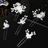 A set of white pearl flower bridal hair clips with silver accents displayed on a dark surface.