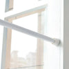A white adjustable telescopic curtain rod extending horizontally across a window frame.