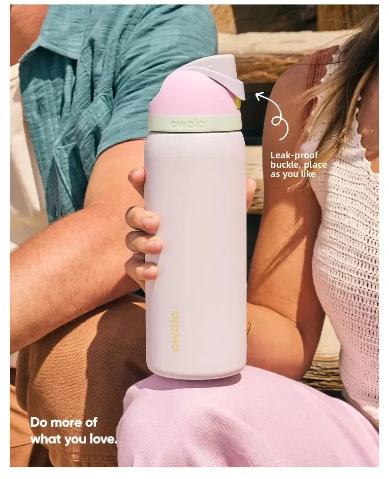 A person holds a pink Owala insulated water bottle with a straw against a light background.