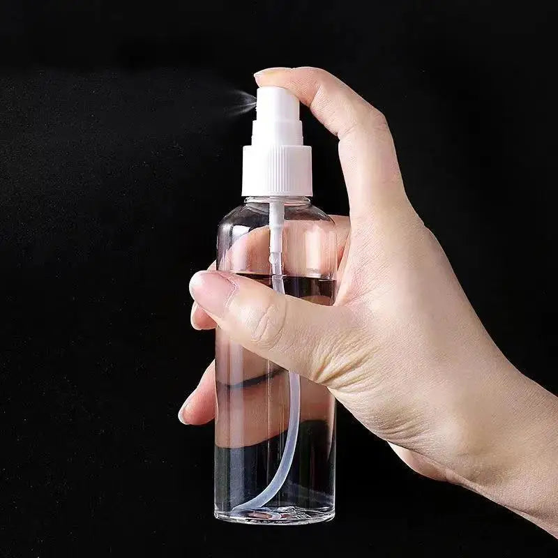 A hand is spraying liquid from a clear glass bottle with a white pump dispenser against a black background.
