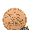 A round copper disk bird bath for garden water with a bird silhouette design.