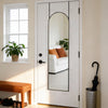A full body wall mirror with an arched top and aluminum frame is mounted on a white door.