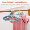Pink and blue plastic hangers with bow designs hanging on a wooden rod.