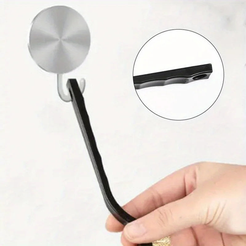 Una mano sostiene un cepillo de limpieza de cocina negro con una cabeza plateada, mostrando el cepillo y su parte desmontable