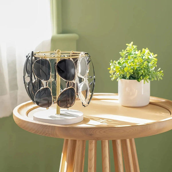 Elegant glasses organizer stand with a gold frame and clear lenses rests on a light wooden table.