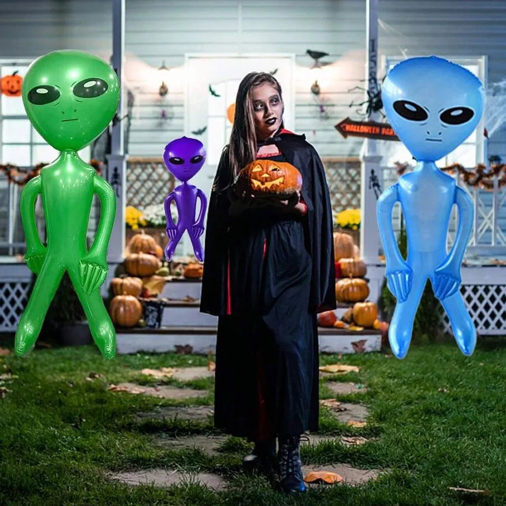 Three inflatable alien decorations in green, purple, and blue standing on grass.
