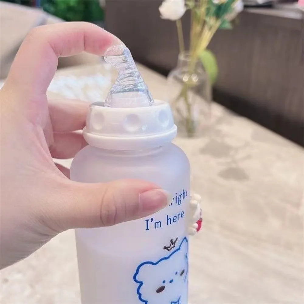 A hand holds a white water bottle with a blue bear design and a clear cap.