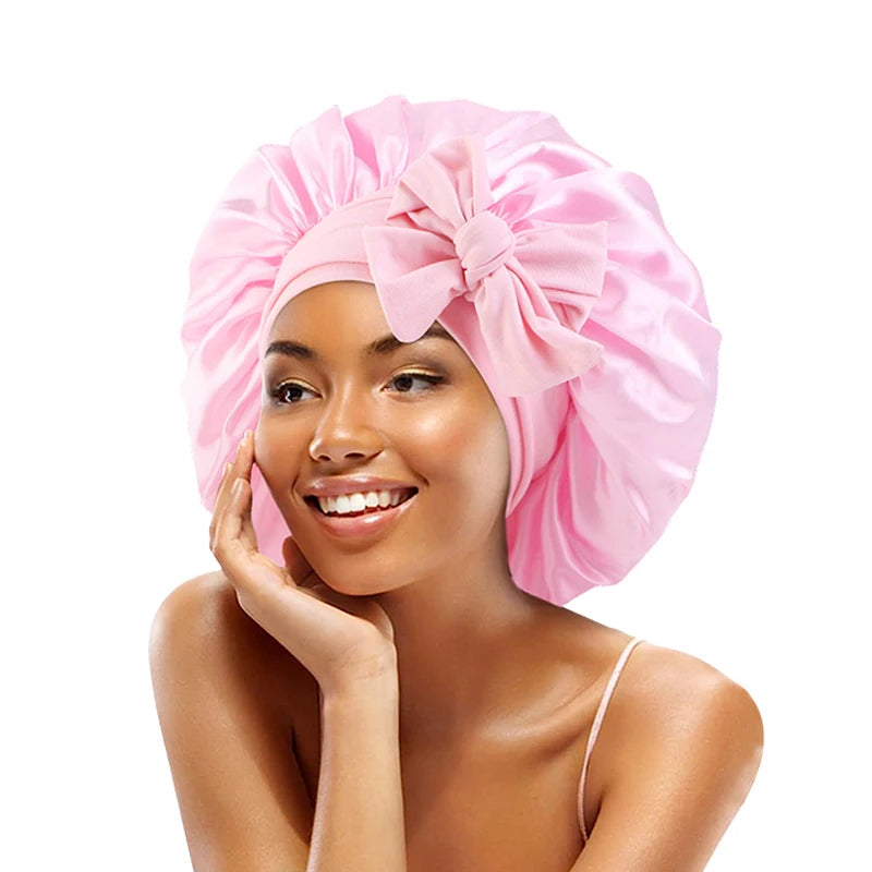 A woman wearing a pink satin sleeping cap with an adjustable tie band.