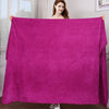 A woman holds up a vibrant magenta microfiber bath towel to display its texture and size.