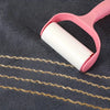 A pink plastic towel hanger holds a roll of white coral fleece towel with gold stripes on a dark gray towel.